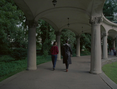 a woman walking down a sidewalk under a covered walkway