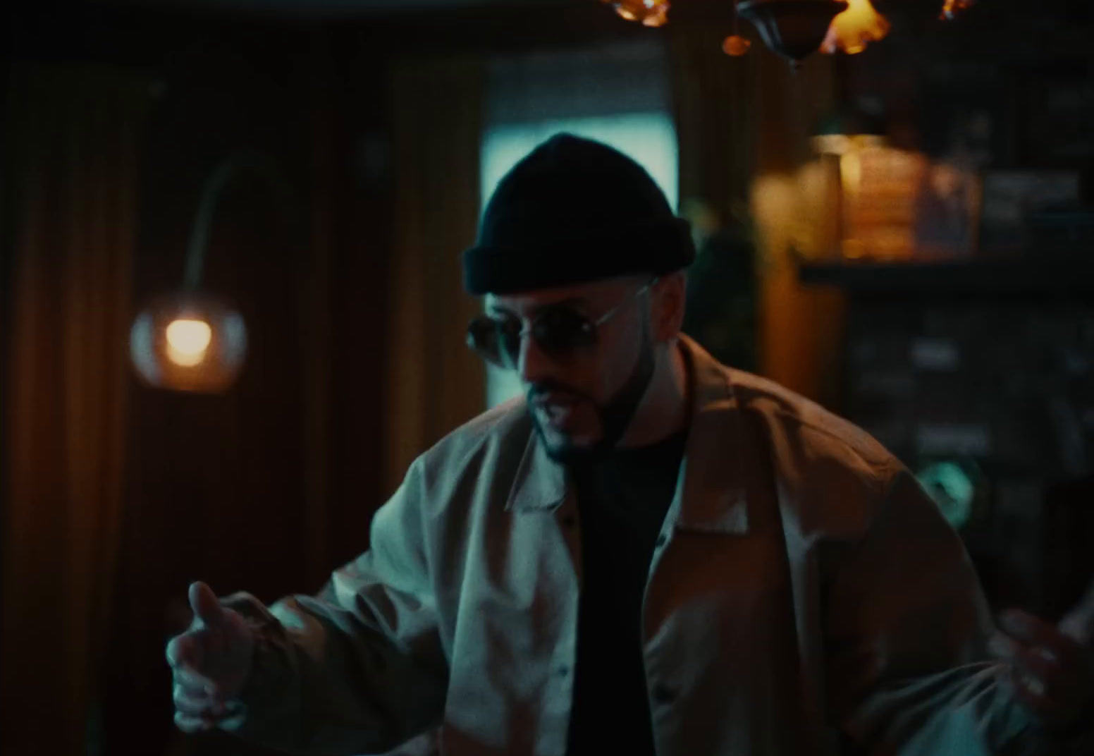 a man in a hat and sunglasses standing in a dark room