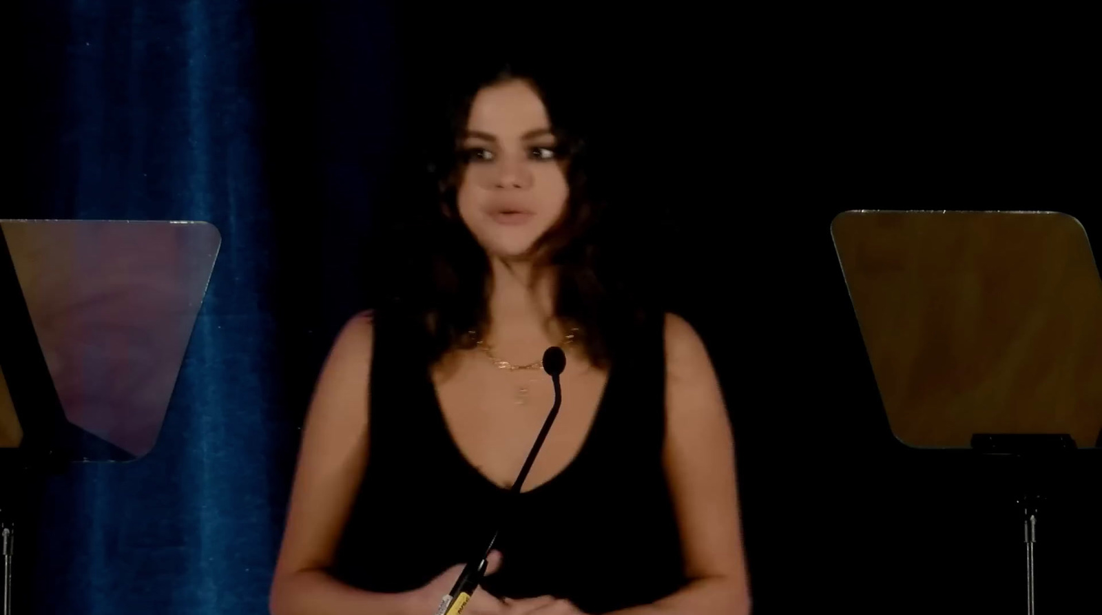 a woman standing at a podium in front of a microphone