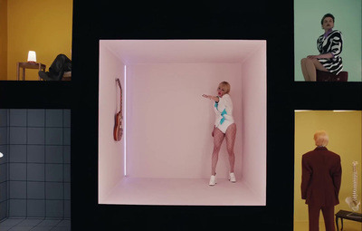 a woman in a white bodysuit standing in a pink room