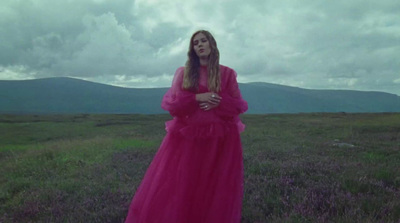 a woman in a pink dress standing in a field