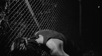 a person leaning against a chain link fence