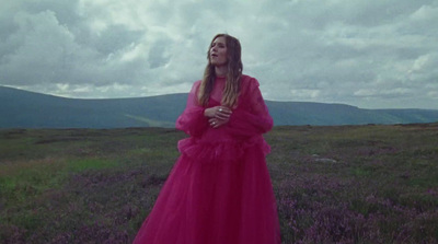 a woman in a pink dress standing in a field