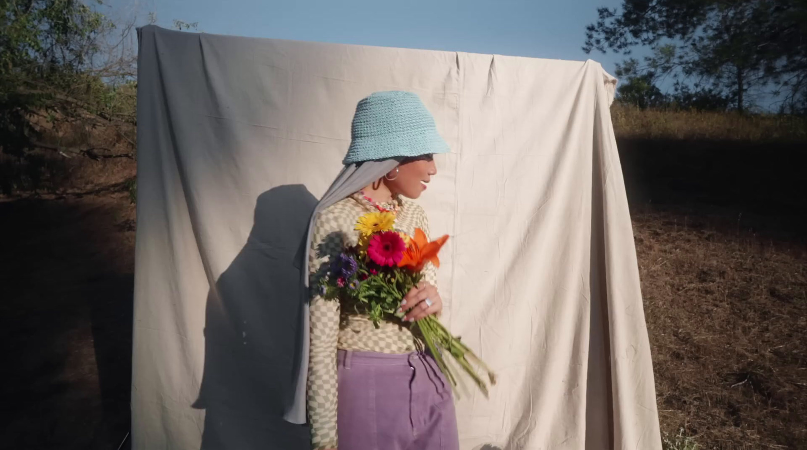 a woman in a blue hat holding a bouquet of flowers