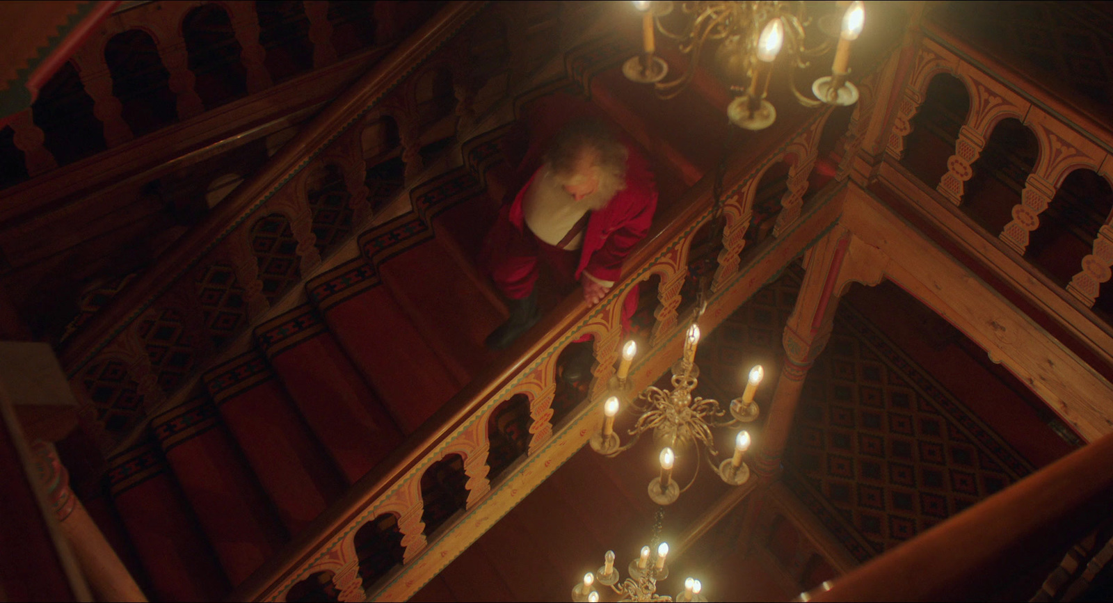 a man in a red jacket standing on a stair case