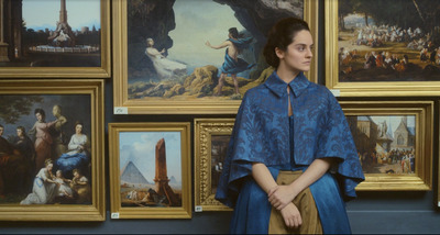 a woman standing in front of a wall of paintings