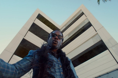 a man in a fur vest standing in front of a tall building