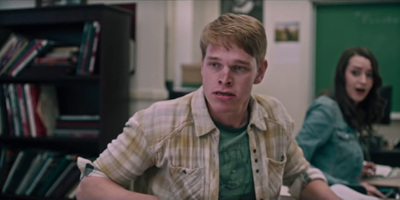 a young man sitting at a desk in front of a woman