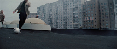 a man kicking a soccer ball on top of a roof