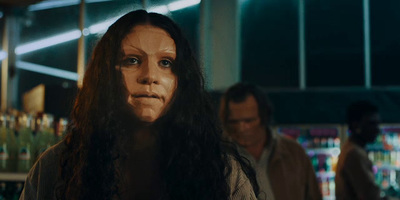 a woman with long hair standing in front of a bar