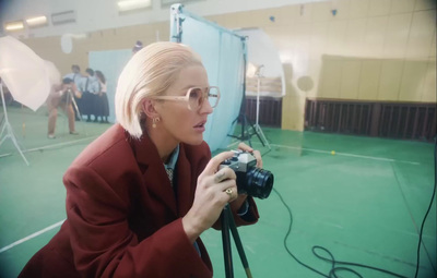 a woman in a red jacket is holding a camera