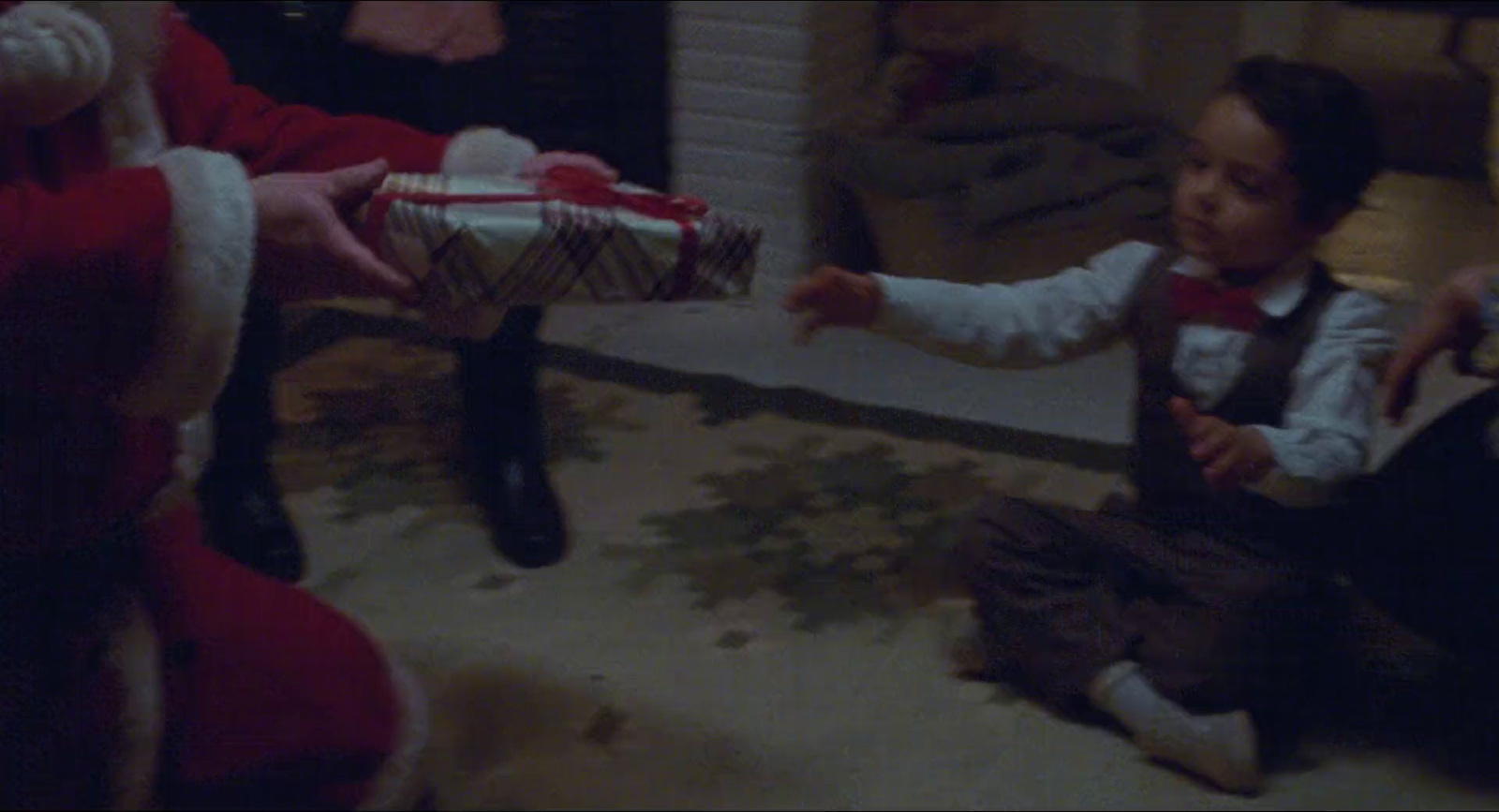 a little boy holding a christmas present in a living room