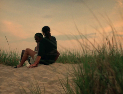 a couple of people sitting on top of a sandy beach