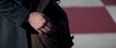 a man in a trench coat is holding his hand out