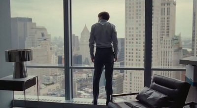 a man standing in front of a window looking out at a city