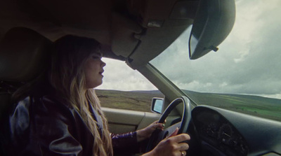 a woman driving a car on a cloudy day