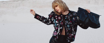 a woman in a black floral shirt holding a black bag