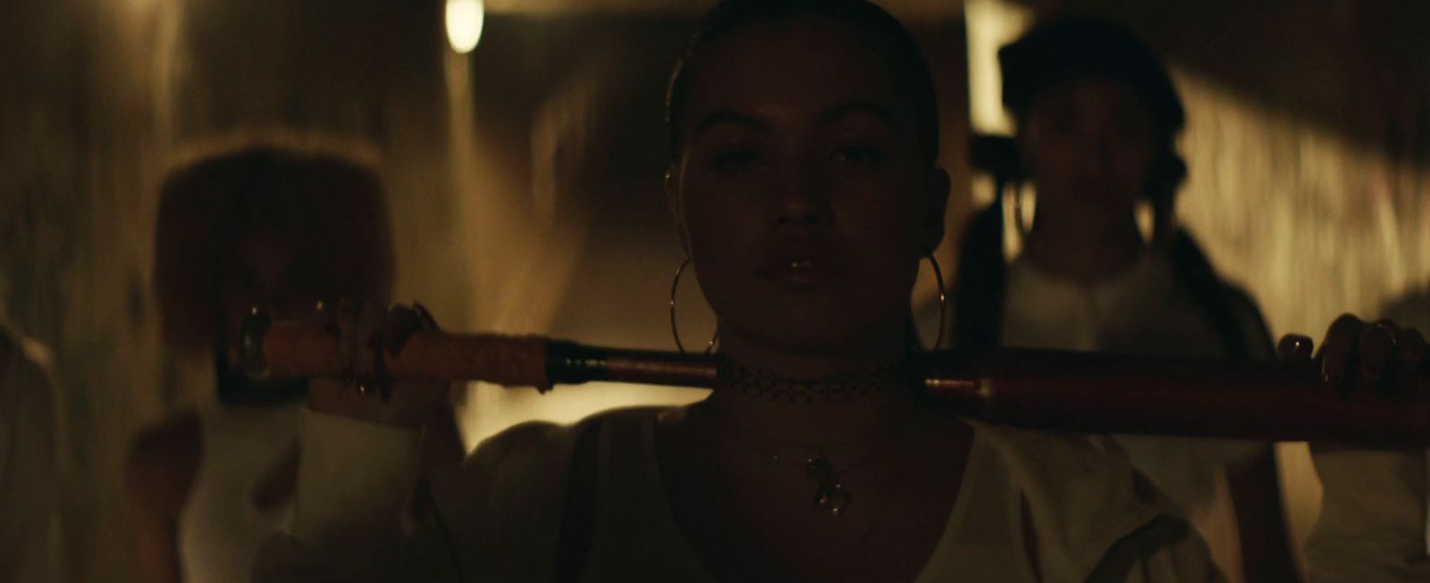 a woman holding a baseball bat in a dimly lit room