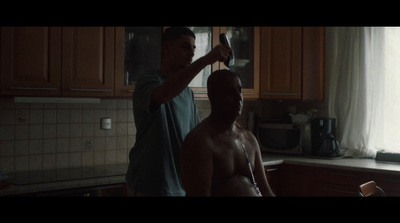 two men standing in a kitchen brushing their hair