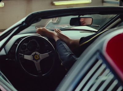 a person sitting in a car with their feet on the steering wheel