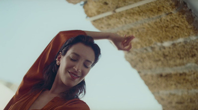 a woman in a red dress standing next to a stone wall