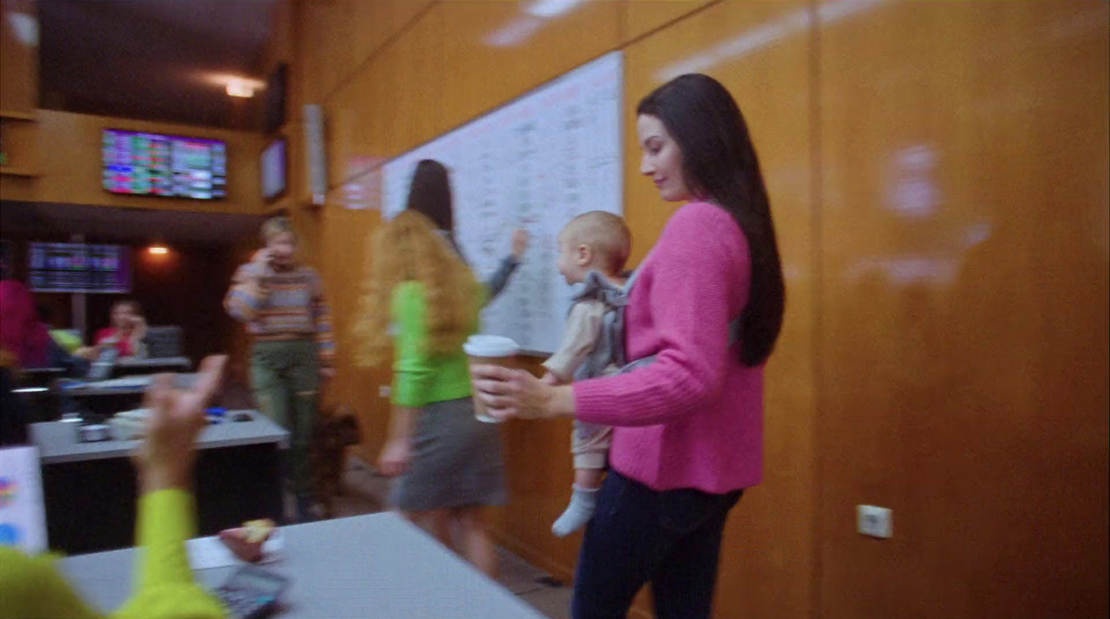 a woman in a pink jacket is holding a baby