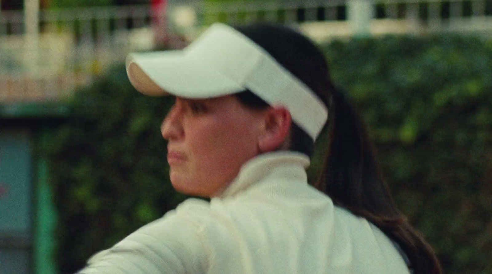 a woman in a white shirt and hat playing tennis