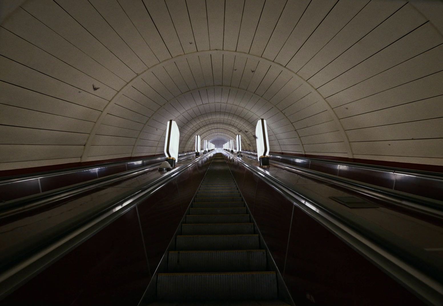 an escalator going down a tunnel with a few escalators