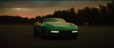 a green sports car driving down a road