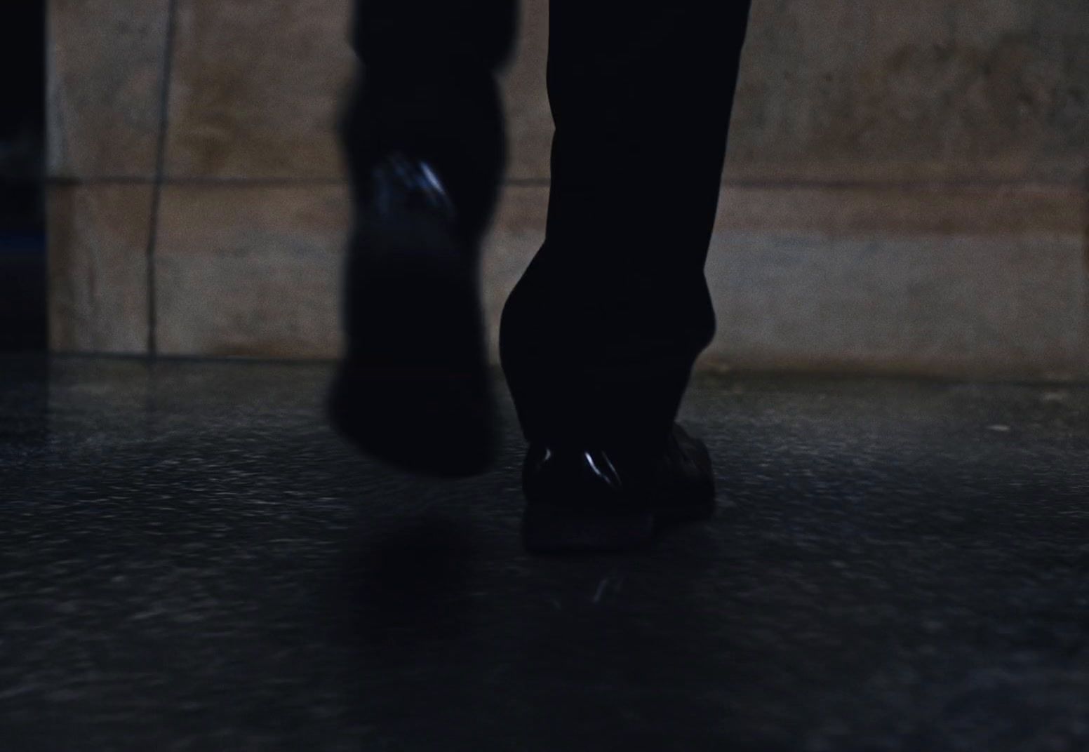 a person's feet in black shoes on a black floor