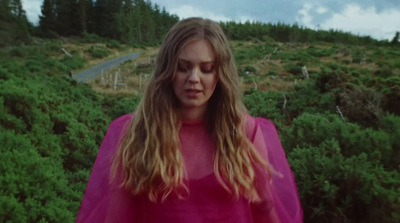 a woman in a pink dress standing in a field