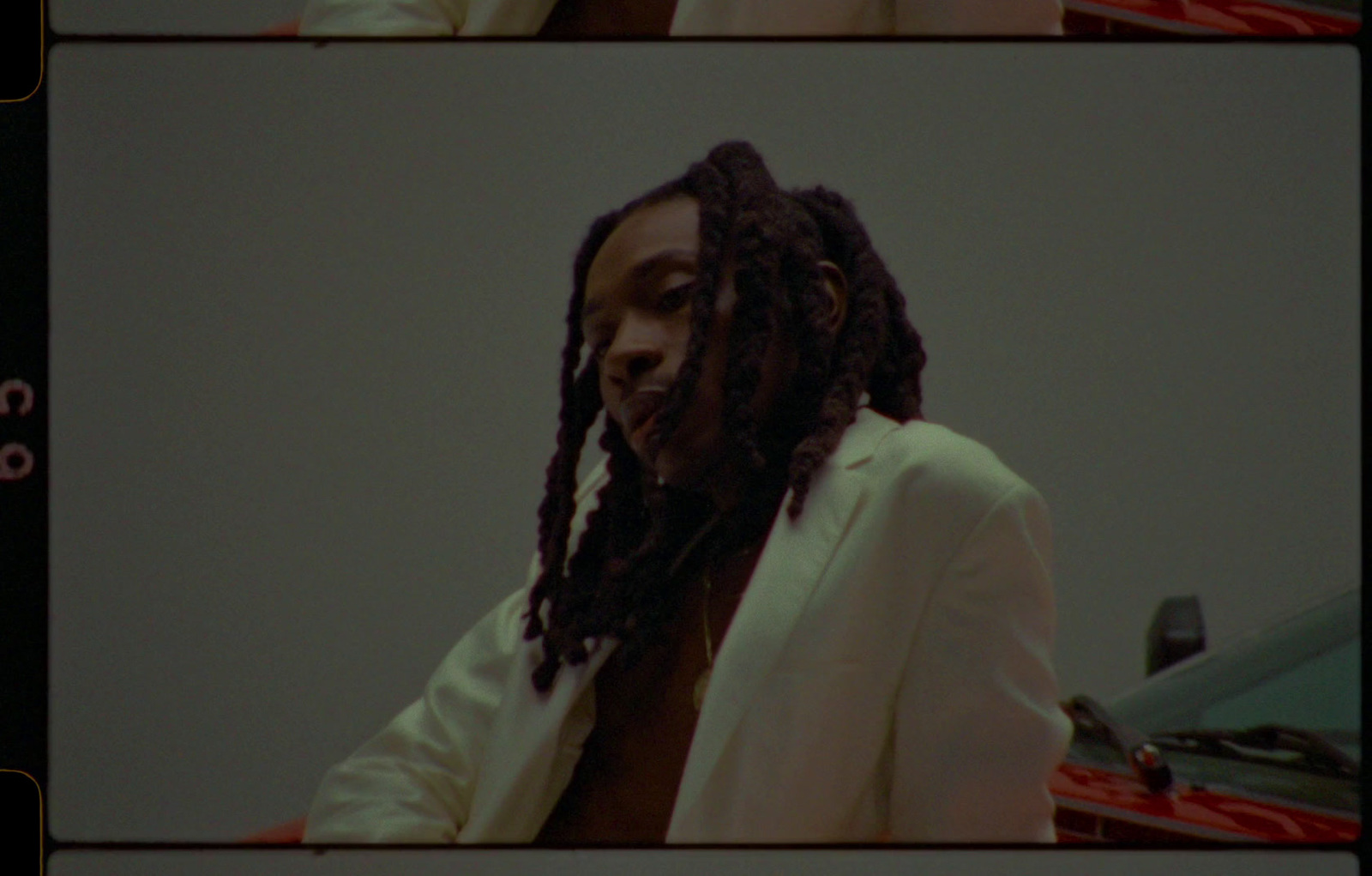 a man with dreadlocks standing in front of a car