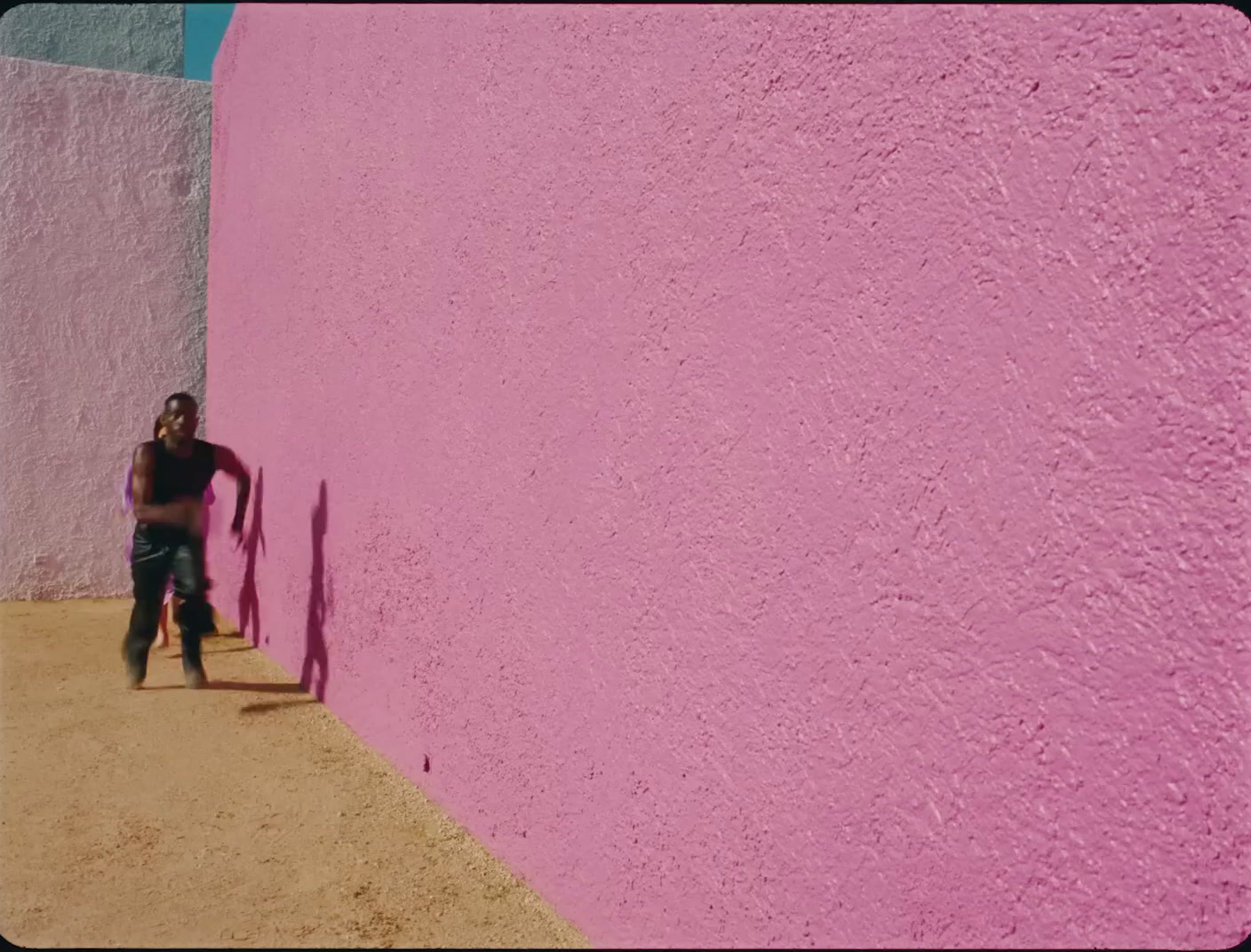 a man standing next to a pink wall