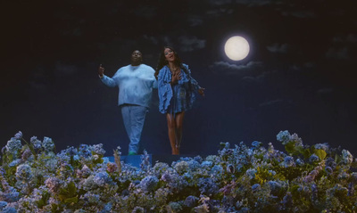 a man and a woman standing in a field of flowers under a full moon