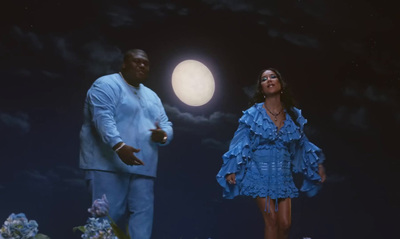 a woman in a blue dress standing next to a man in a white suit