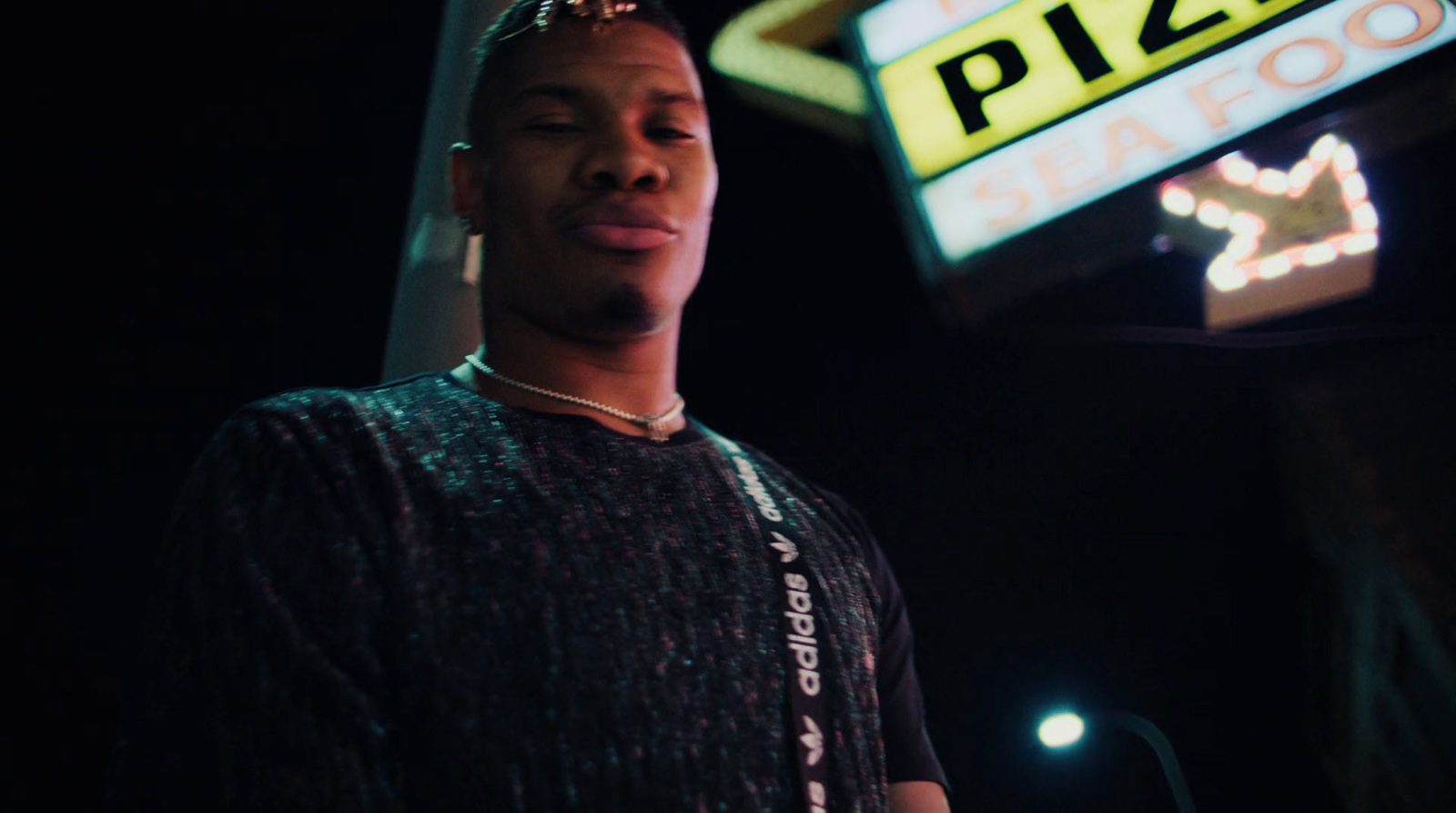 a man standing in front of a pizza sign