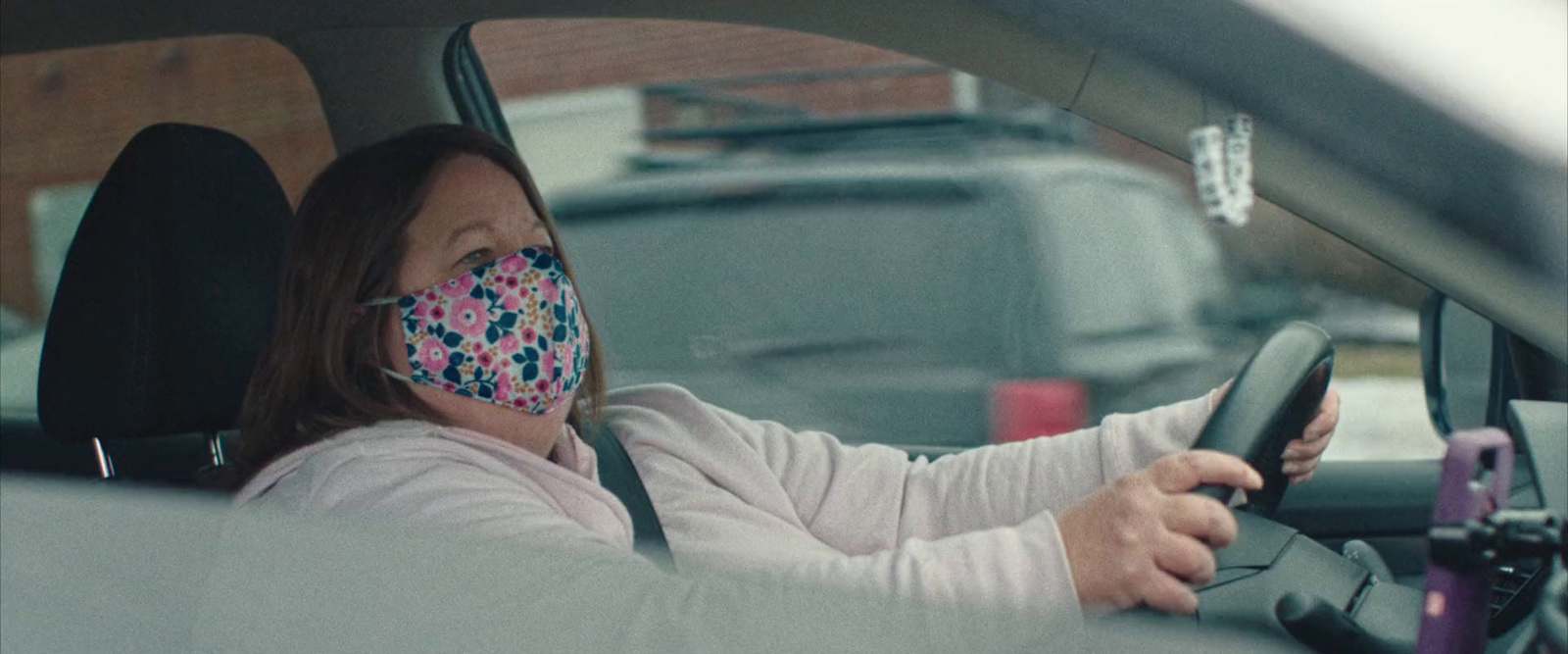 a woman wearing a face mask while driving a car