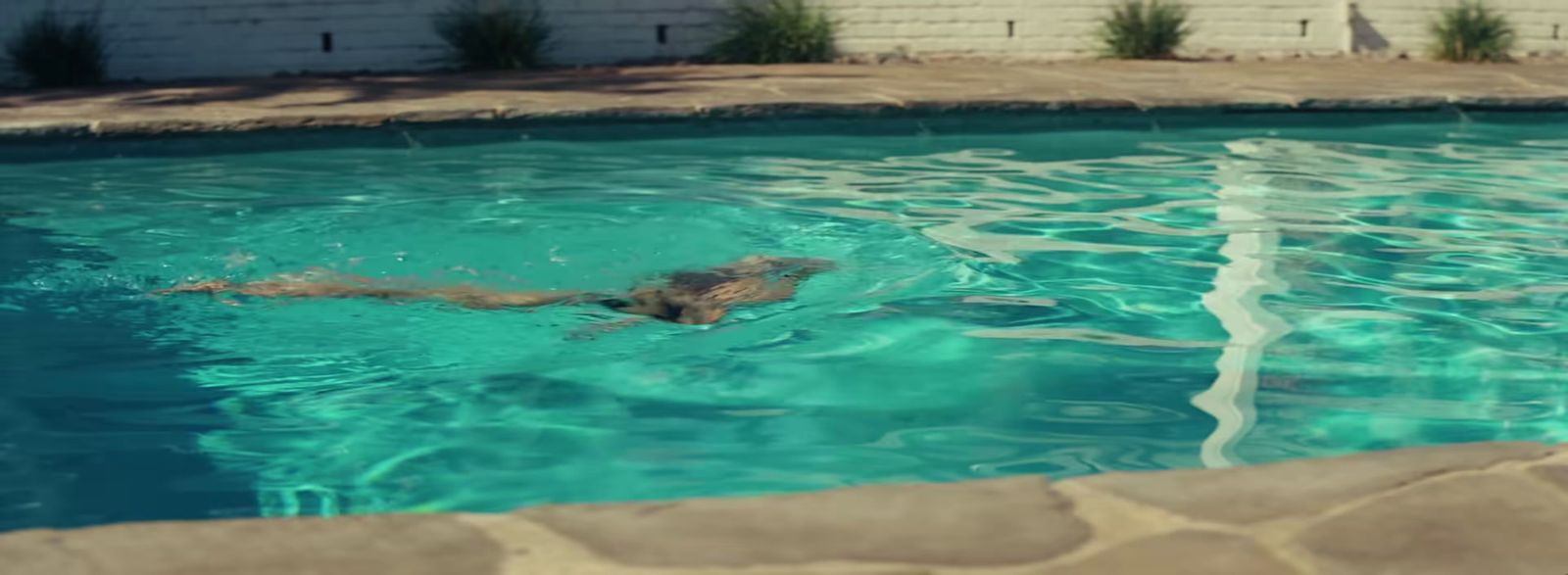 a man is swimming in a pool with clear blue water