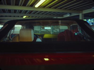 a man driving a red car in a parking garage