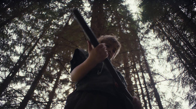 a woman holding a gun in a forest