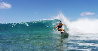 a woman riding a wave on top of a surfboard