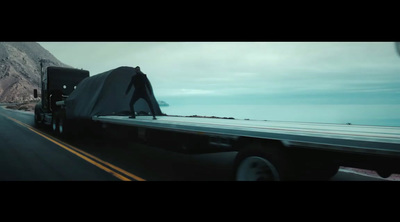 a semi truck driving down a highway next to a mountain