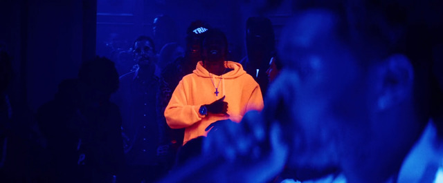 a man in a yellow hoodie standing in front of a crowd