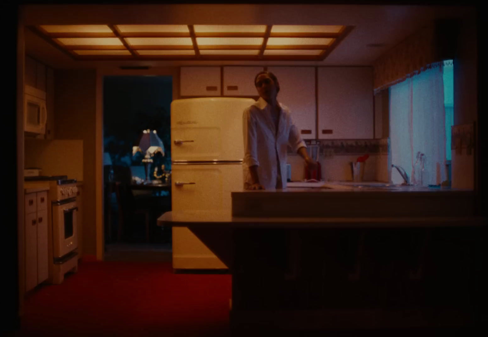 a woman standing in a kitchen next to a refrigerator