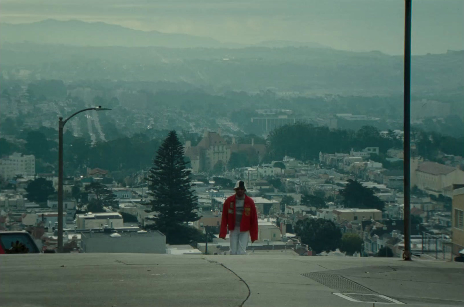 a man in a red jacket is standing on a hill