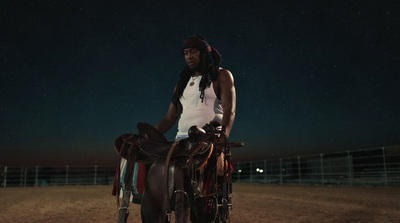 a man standing next to a horse in a dirt field