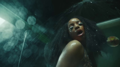 a woman with long hair standing under a shower