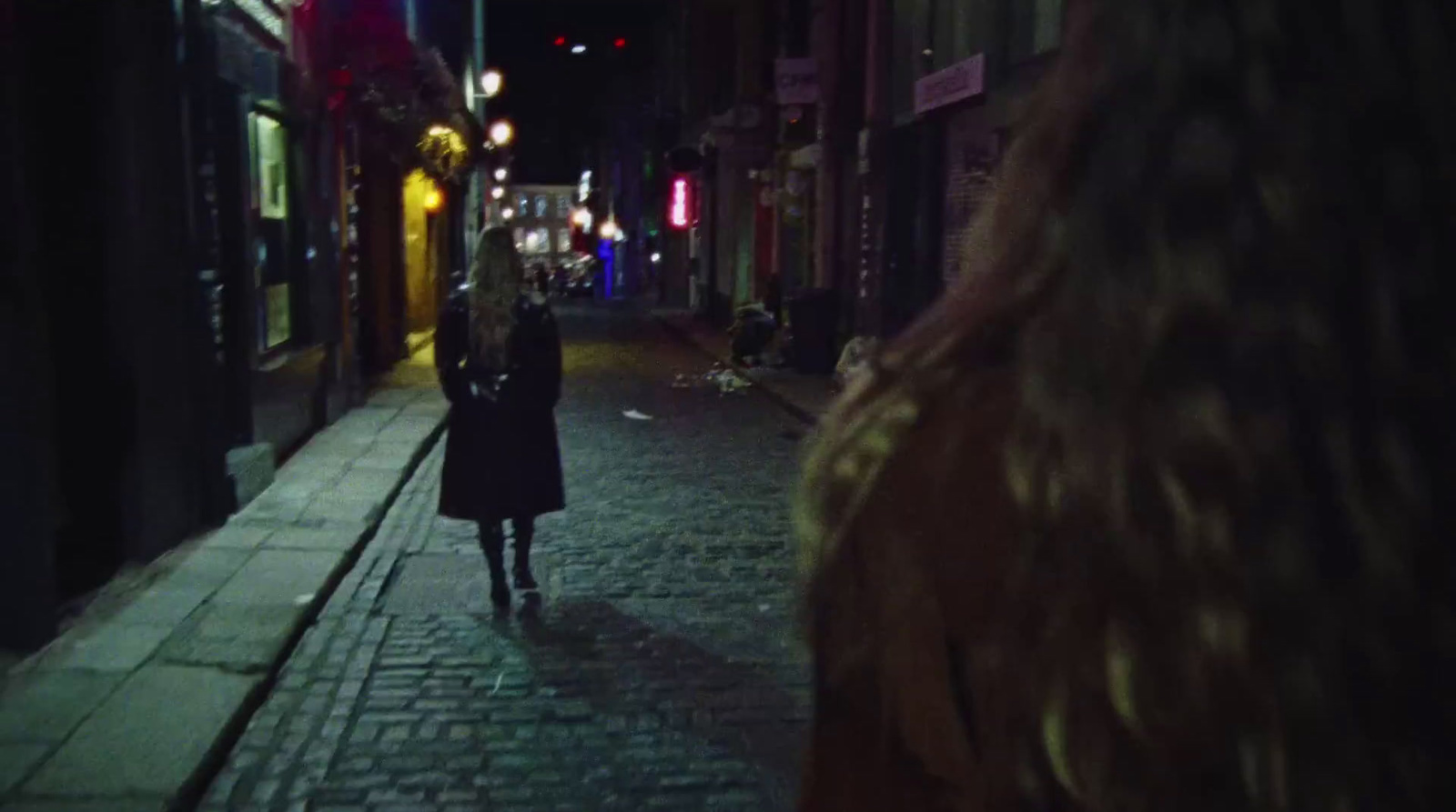 a woman walking down a street at night