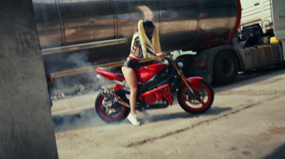 a woman riding a red motorcycle down a street