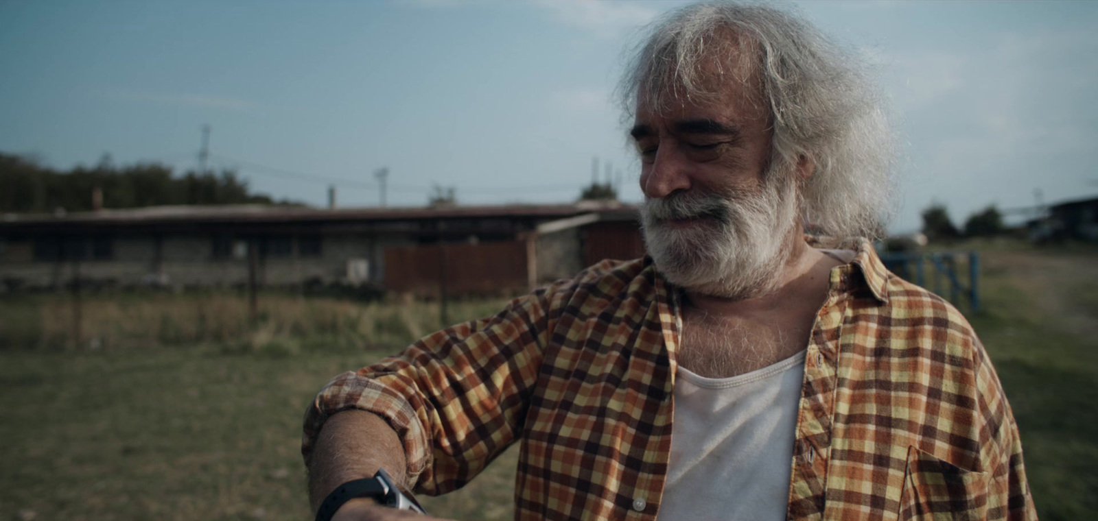 a man with white hair and a beard standing in a field